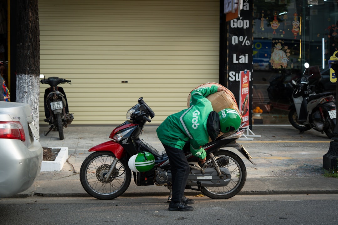 Grab rider loading his motorbike with a large bag.