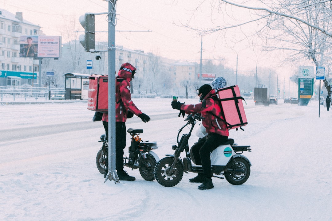 Delivery workers on scooters in snowy city street